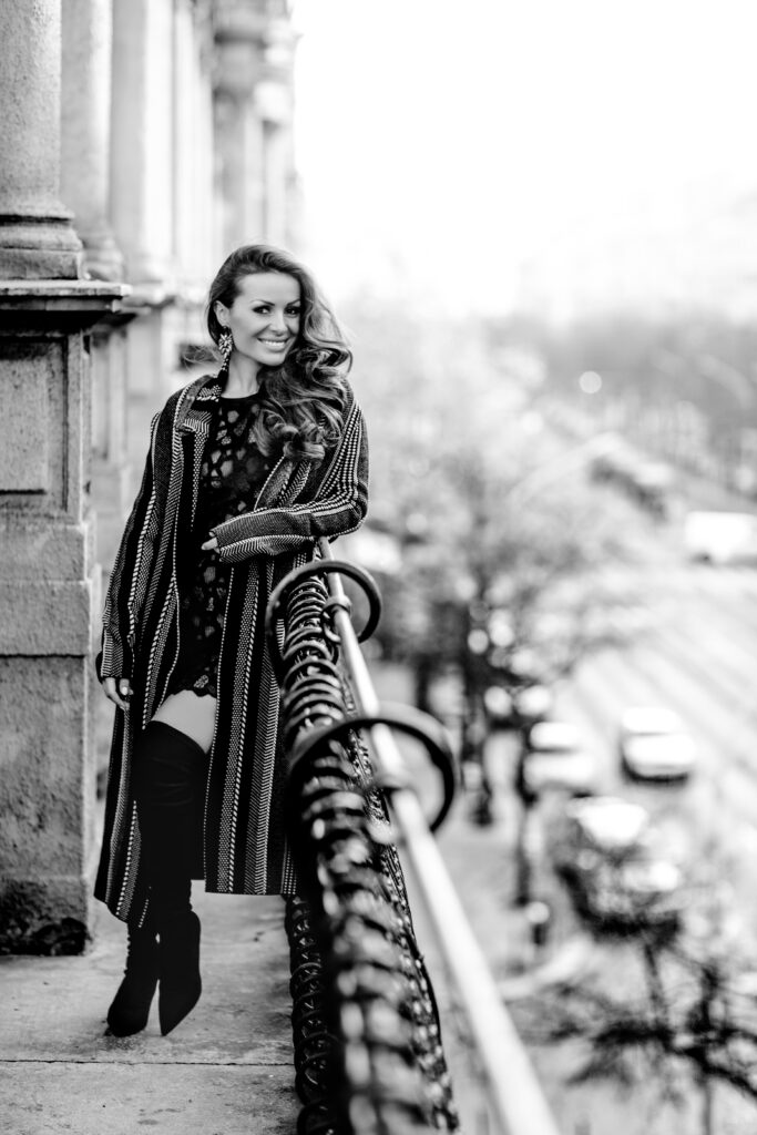 Black-and-white image of a woman in a coat on a balcony – portrait photography by Takács Bori, Budapest