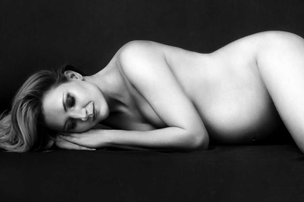Black-and-white image of a reclining woman against a dark backdrop – boudoir photography by Takács Bori, Budapest