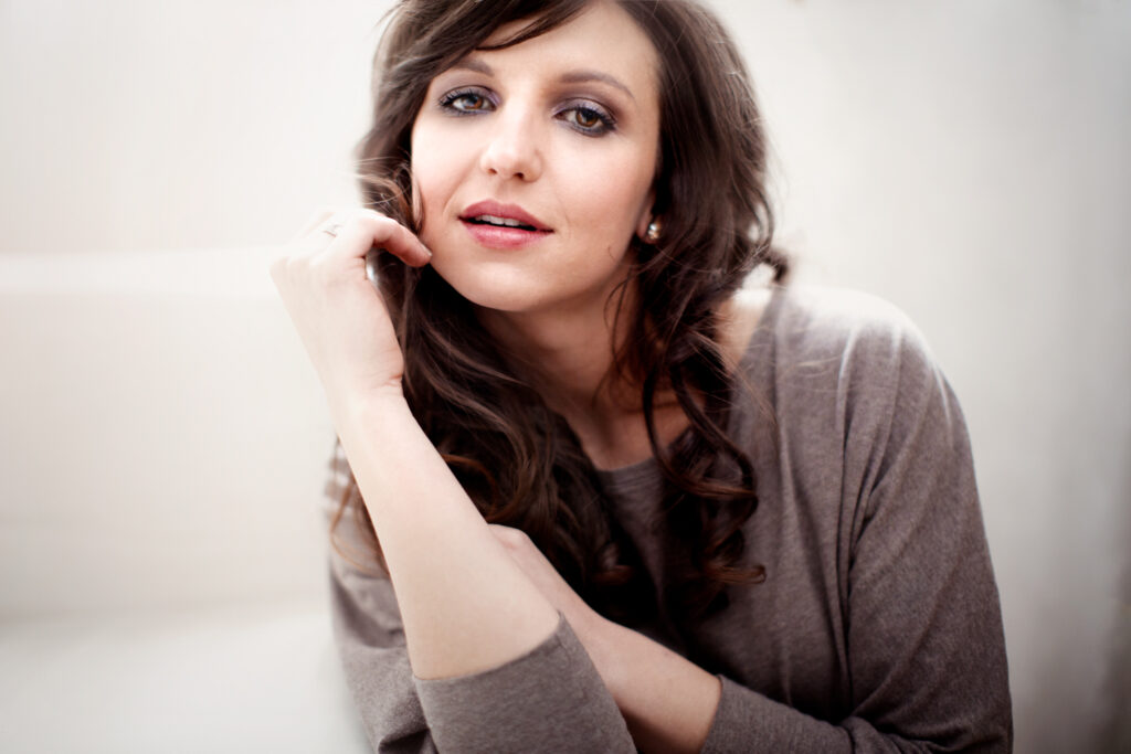 Seated dark-haired woman in warm tones – portrait photography by Takács Bori, Budapest